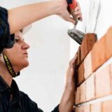 Bricklayer wearing safety gear while working on a brick wall